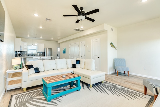 living room featuring sink, ceiling fan, and light hardwood / wood-style flooring