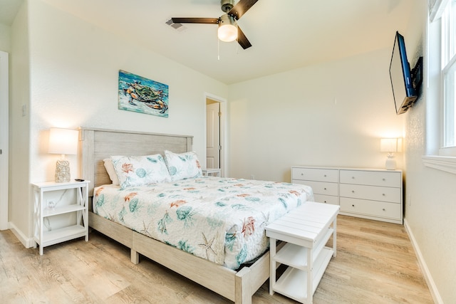 bedroom featuring light hardwood / wood-style flooring, ceiling fan, and multiple windows