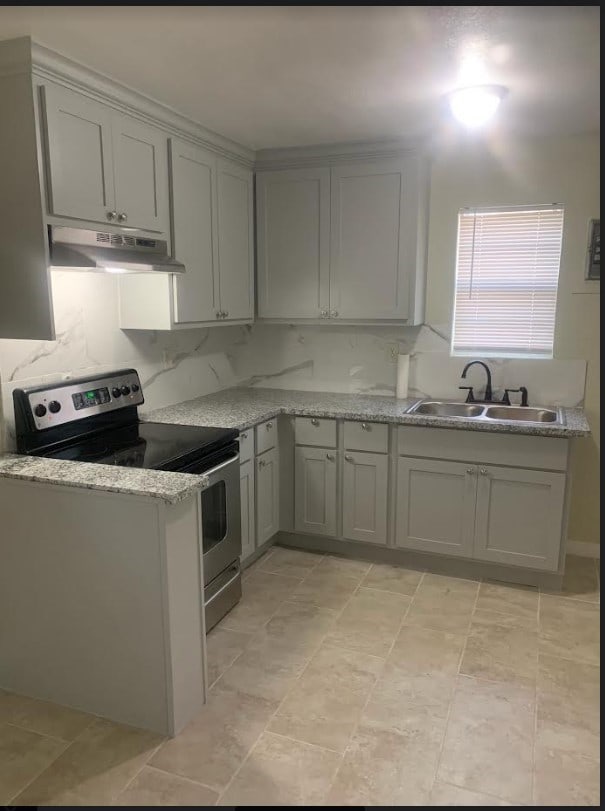 kitchen with light tile patterned floors, gray cabinets, sink, stainless steel electric stove, and light stone counters