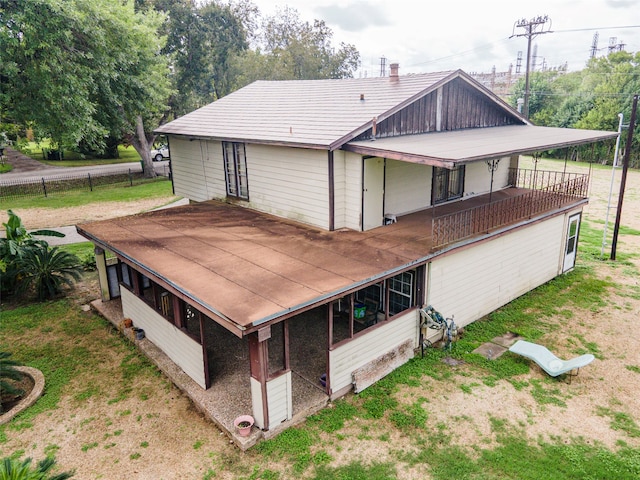 back of property featuring a balcony and a lawn