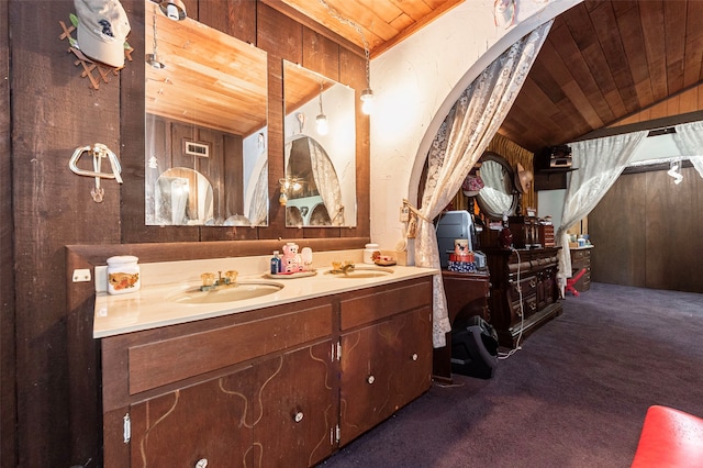 bathroom with wood walls, lofted ceiling, double sink vanity, and wood ceiling