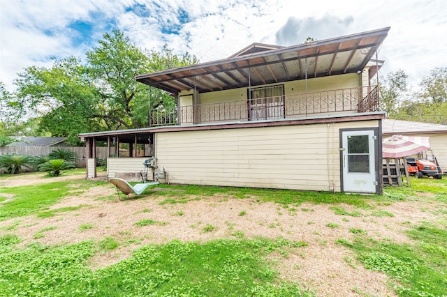 back of house featuring a balcony and a yard