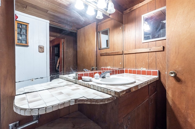 bathroom with wood ceiling, wooden walls, and vanity