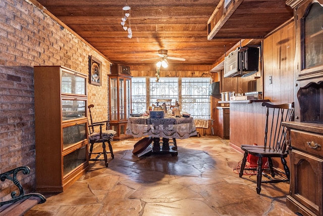 home office featuring wood ceiling, wood walls, brick wall, and ceiling fan