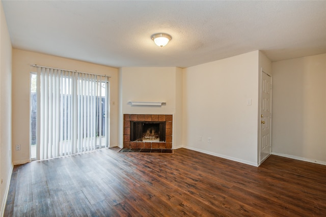 unfurnished living room featuring a textured ceiling, dark hardwood / wood-style floors, and a tiled fireplace