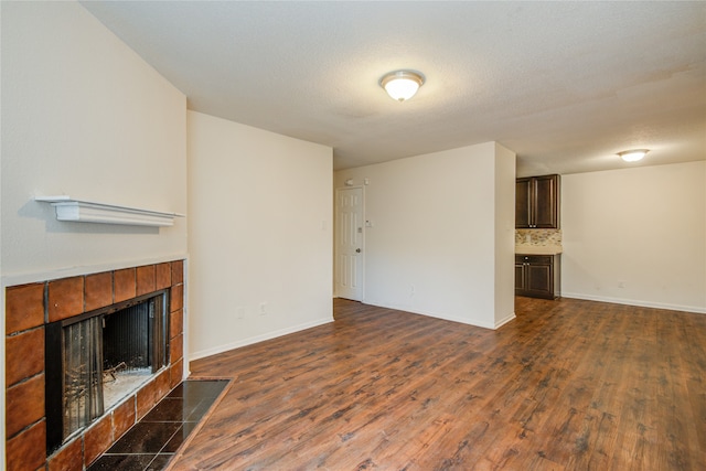 unfurnished living room with dark hardwood / wood-style flooring and a tile fireplace