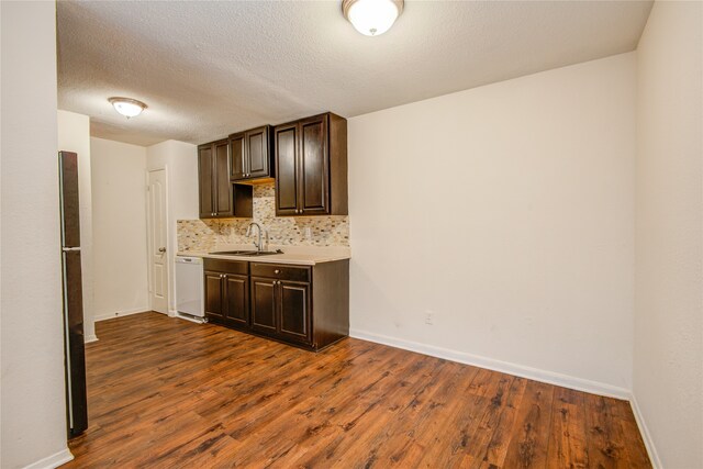 kitchen featuring dark wood-type flooring, sink, dishwasher, tasteful backsplash, and dark brown cabinetry