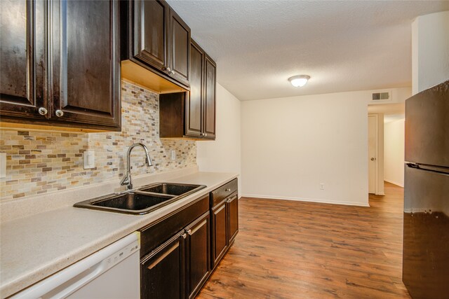 kitchen with stainless steel fridge, sink, dishwasher, tasteful backsplash, and hardwood / wood-style flooring