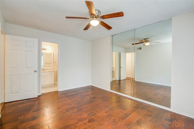 unfurnished bedroom with ensuite bath, dark hardwood / wood-style flooring, and ceiling fan