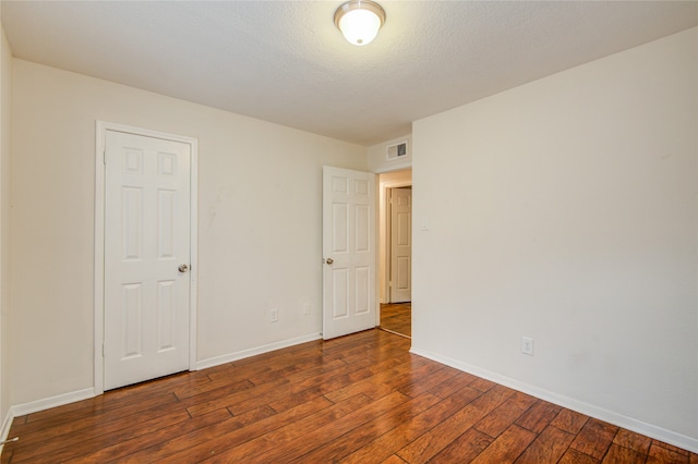 unfurnished bedroom with dark hardwood / wood-style floors and a textured ceiling