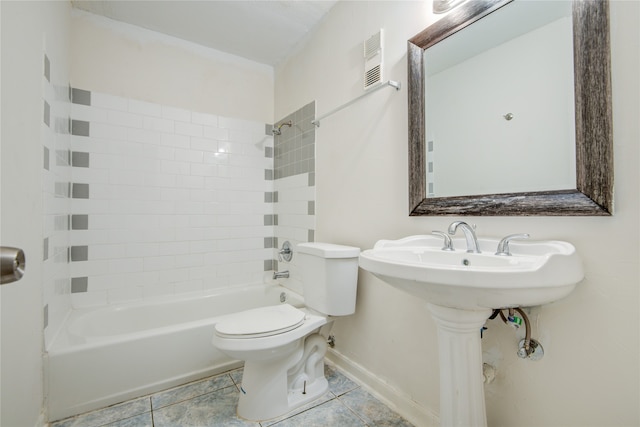 bathroom featuring tiled shower / bath, toilet, and tile floors