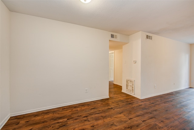 empty room featuring a textured ceiling and dark hardwood / wood-style flooring