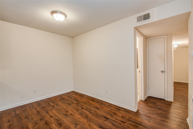 empty room with dark hardwood / wood-style floors and a textured ceiling