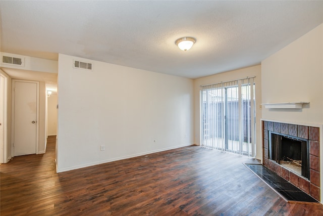 unfurnished living room with a textured ceiling, dark hardwood / wood-style floors, and a fireplace