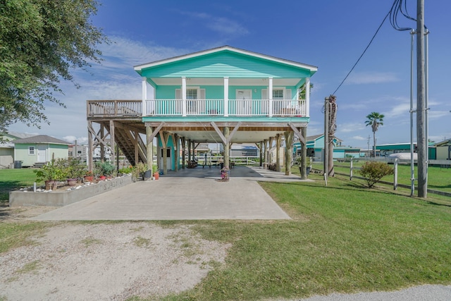 rear view of house with a wooden deck, a balcony, a yard, and a patio