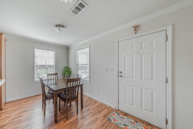 dining area featuring crown molding, a textured ceiling, and light wood-type flooring