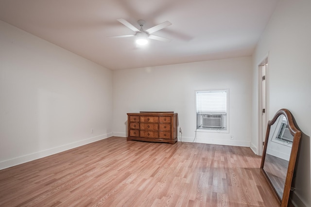 empty room featuring light wood finished floors, cooling unit, a ceiling fan, and baseboards