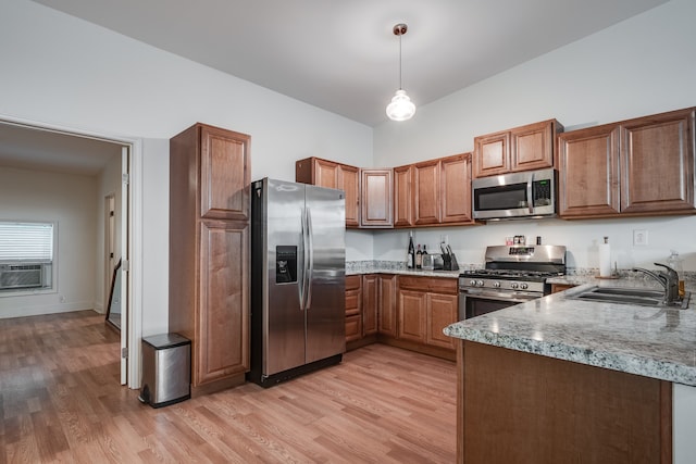 kitchen with light stone countertops, light hardwood / wood-style floors, pendant lighting, sink, and appliances with stainless steel finishes