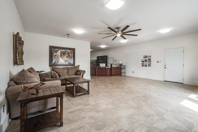 living area with a ceiling fan and baseboards