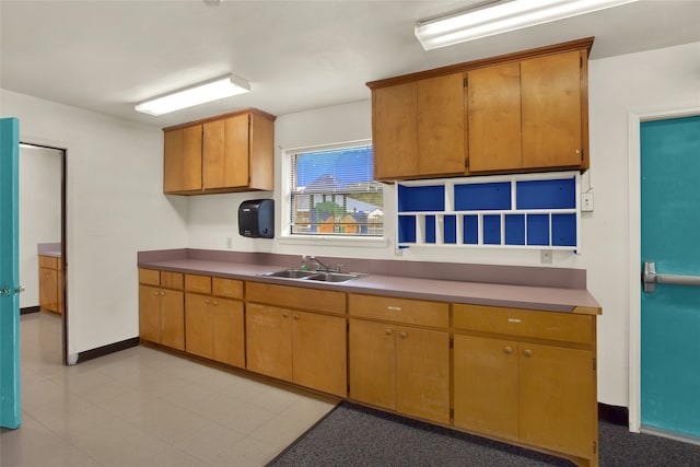 kitchen featuring brown cabinetry, baseboards, and a sink