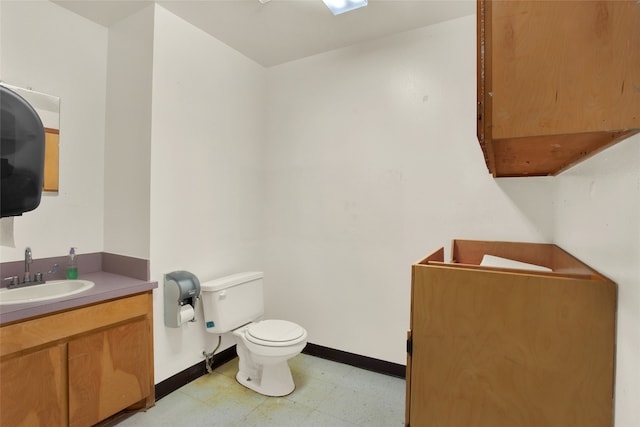 half bathroom featuring tile patterned floors, baseboards, vanity, and toilet