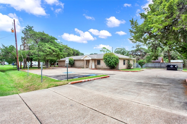 single story home featuring brick siding, uncovered parking, a front yard, and fence
