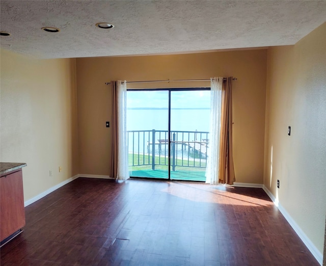 unfurnished room with dark hardwood / wood-style floors and a textured ceiling