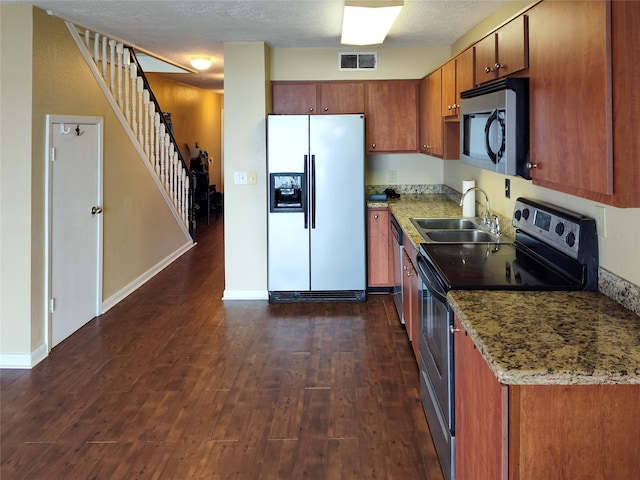 kitchen with dark wood-type flooring, appliances with stainless steel finishes, light stone countertops, and sink