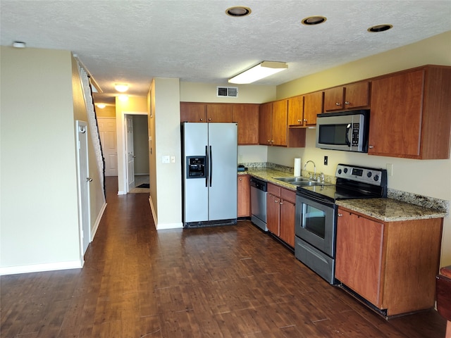 kitchen with appliances with stainless steel finishes, light stone counters, dark hardwood / wood-style floors, and sink