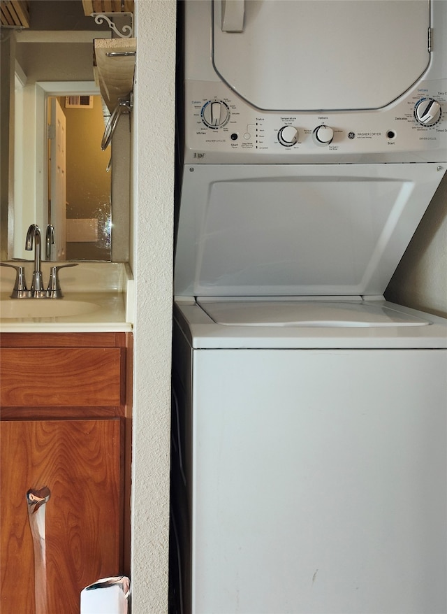 clothes washing area featuring sink and stacked washing maching and dryer