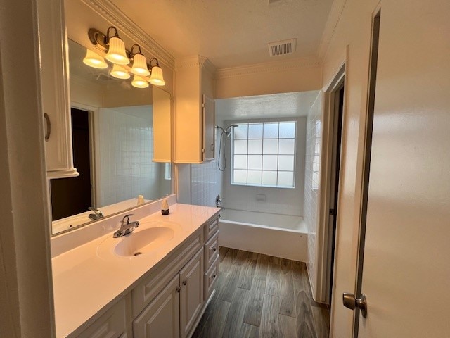 bathroom with  shower combination, ornamental molding, large vanity, and hardwood / wood-style flooring