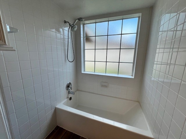 bathroom with tiled shower / bath combo and a wealth of natural light