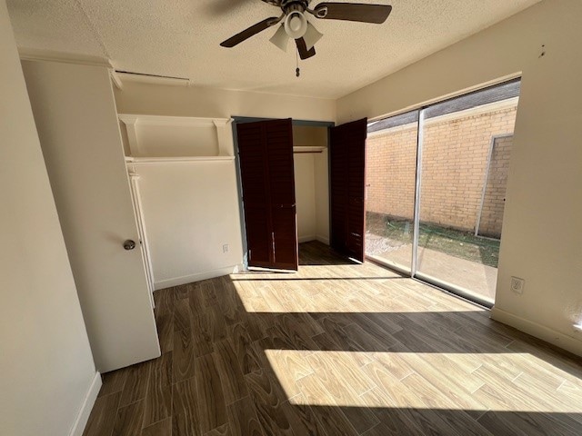 unfurnished bedroom with dark hardwood / wood-style floors, a textured ceiling, and ceiling fan