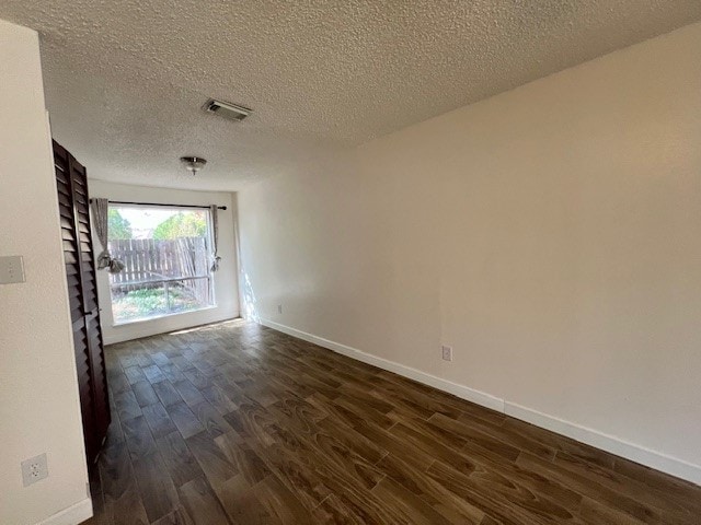 unfurnished room featuring a textured ceiling and dark hardwood / wood-style flooring