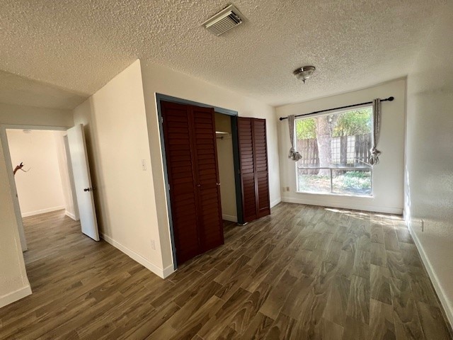 hall with a textured ceiling and dark hardwood / wood-style floors