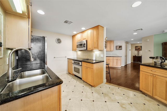 kitchen with light tile floors, black appliances, backsplash, dark stone countertops, and sink