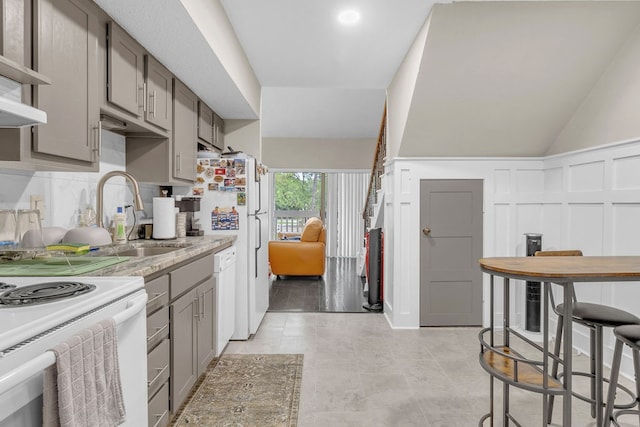 kitchen with lofted ceiling, white dishwasher, sink, gray cabinets, and light tile patterned floors