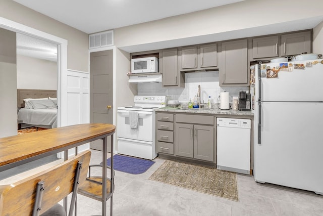 kitchen featuring backsplash, sink, light tile patterned flooring, and white appliances