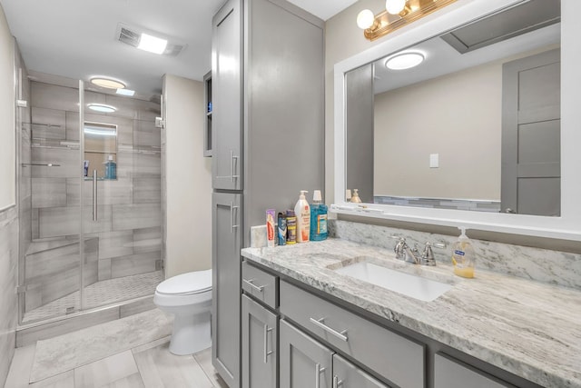 bathroom featuring tile patterned flooring, vanity, toilet, and walk in shower