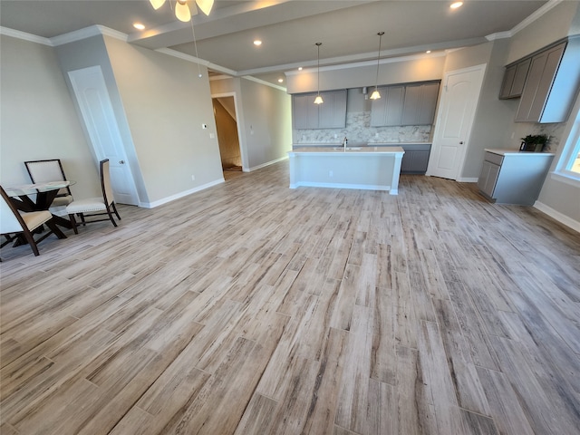 kitchen featuring an island with sink, sink, pendant lighting, and light hardwood / wood-style flooring