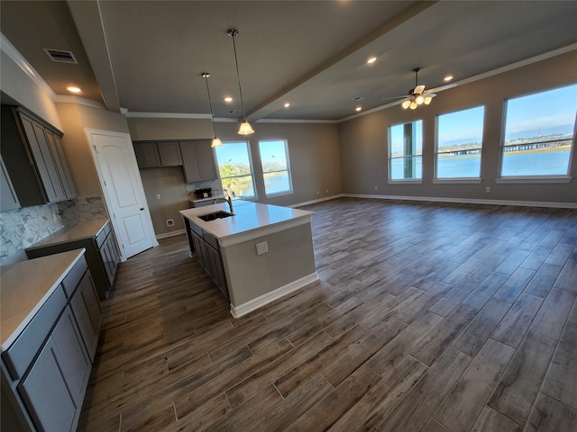 kitchen with decorative light fixtures, a center island with sink, dark hardwood / wood-style flooring, and tasteful backsplash