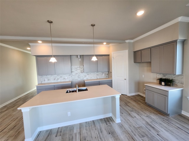 kitchen with decorative light fixtures, gray cabinetry, tasteful backsplash, and a kitchen island with sink