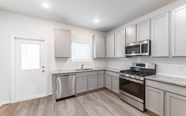 kitchen with gray cabinetry, sink, light hardwood / wood-style floors, and appliances with stainless steel finishes