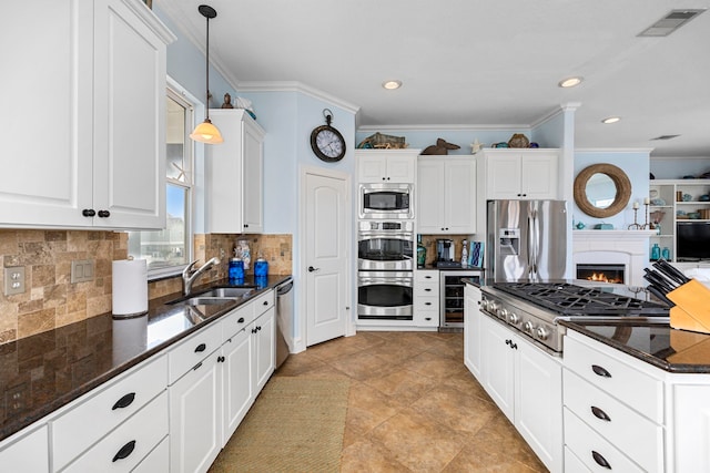 kitchen featuring pendant lighting, white cabinetry, sink, dark stone counters, and stainless steel appliances