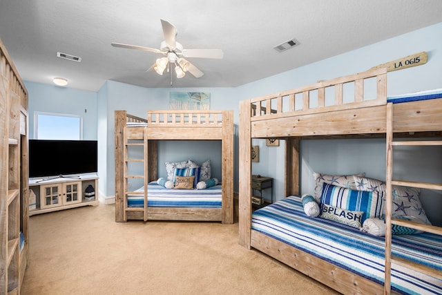 carpeted bedroom featuring ceiling fan and a textured ceiling