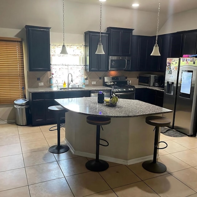 kitchen featuring a kitchen island, appliances with stainless steel finishes, sink, and a breakfast bar area