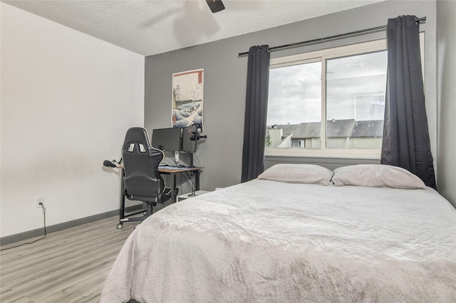 bedroom with light hardwood / wood-style flooring, ceiling fan, and a textured ceiling