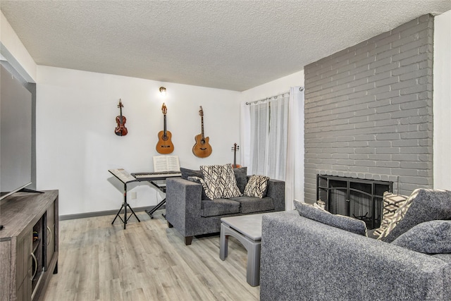 living room featuring a brick fireplace, a textured ceiling, and light hardwood / wood-style floors