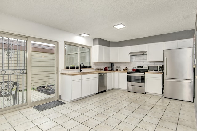 kitchen featuring sink, stainless steel appliances, white cabinetry, and light tile floors