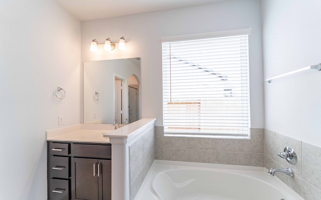 bathroom featuring a bath to relax in, a wealth of natural light, and vanity